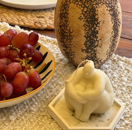 A shape of a woman sitting on the floor and hugging herself decorative candle.