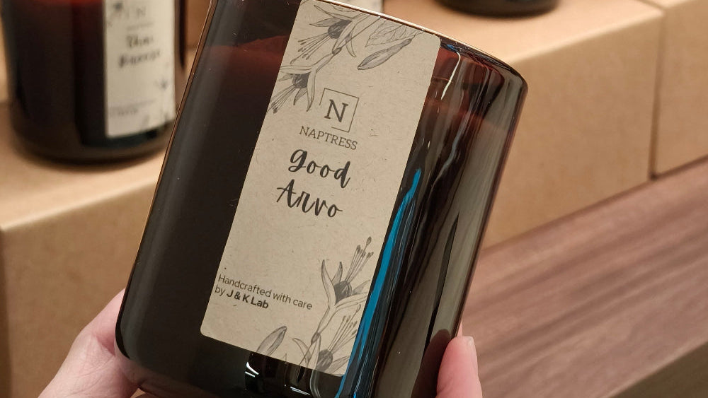 An amber painted candle with a kraft label printed Naptress logo on it