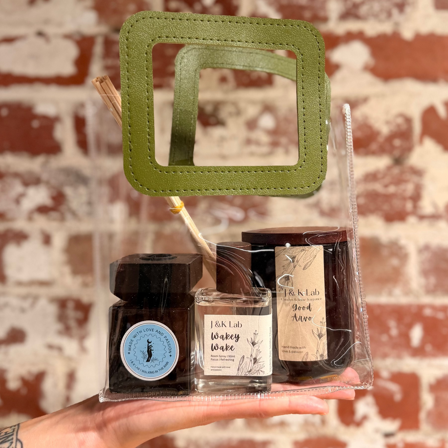 A good arvo candle, a walking in the rain diffuser and Wakey wake room spray in a transparent gift bag with olive green handle. 